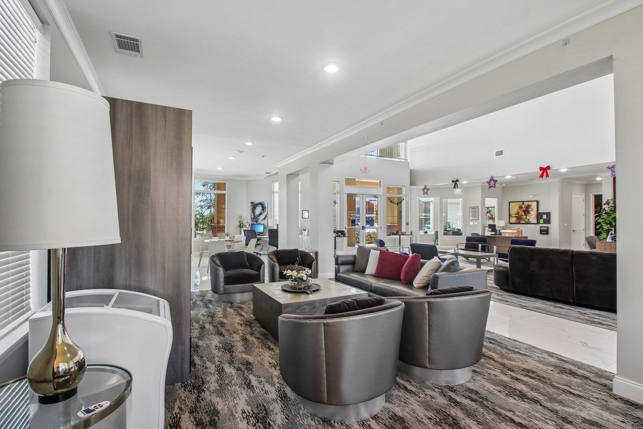 A modern living room with a grey carpet and a variety of seating options.